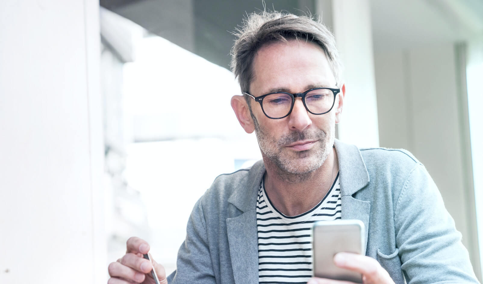 Spokojný investor a klient LYNX ktorý obchoduje na burze za použitia smartphonu